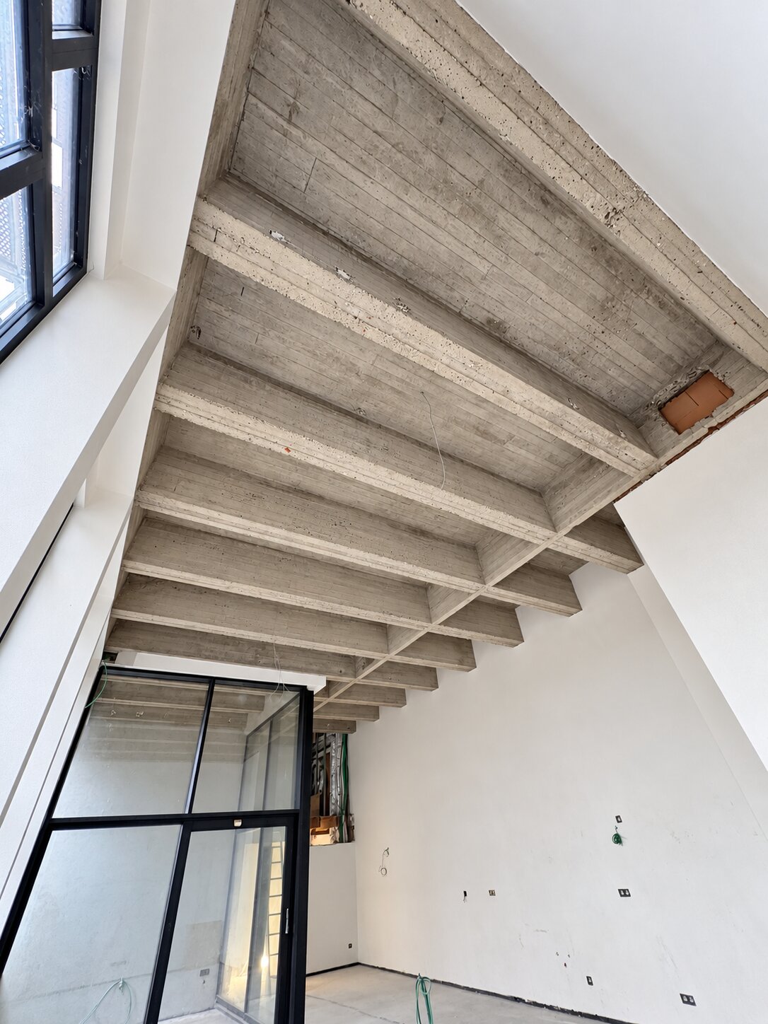 Betonnen plafond met balken en zichtbare structuur in een binnenruimte.