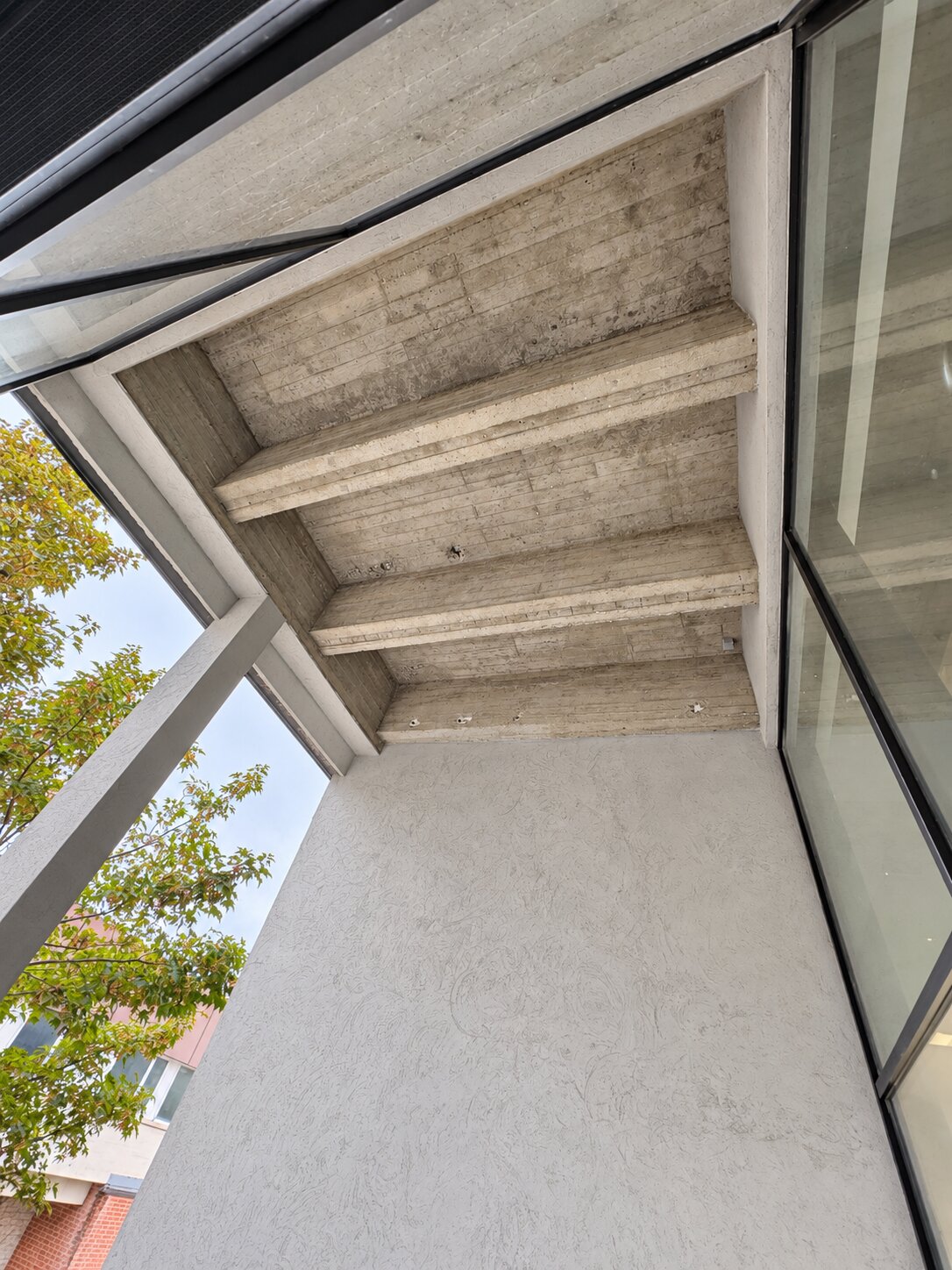 Betonnen plafond en balken boven een buitenruimte.