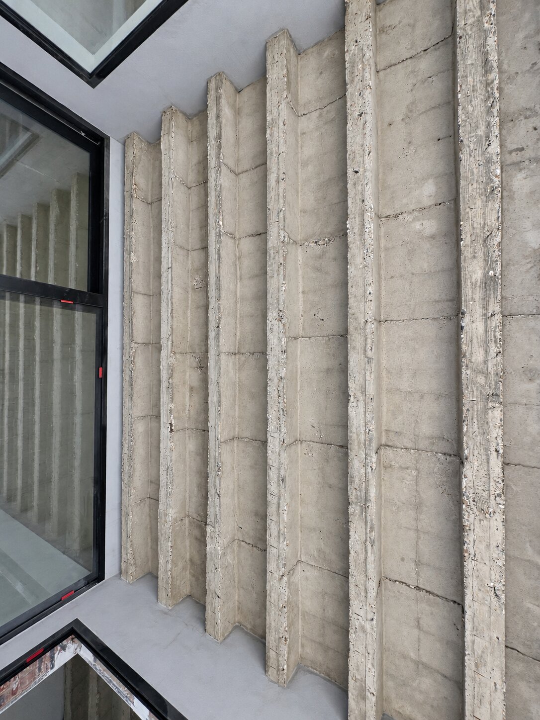 Detail van de ruwe structuur en balken van een betonnen plafond.